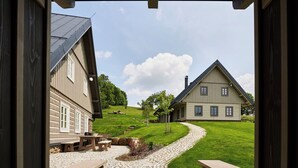 Udsigt gennem en åben døråbning af et hus med en stensti, der fører til en træterrasse.