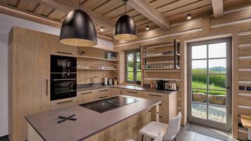 A modern kitchen with wooden cabinetry, a central island, pendant lighting, and a view of the outdoors.