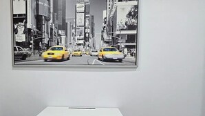 Ein Zimmer mit einem weißen Schreibtisch und einem großen Bild mit Stadtansicht.