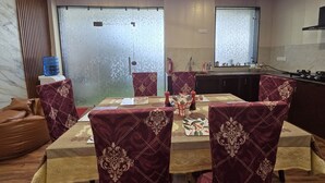 Comedor con una mesa dispuesta para cuatro personas, rodeada de sillas con tapicería estampada.