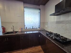 Een keuken met een spoelbak, kraan, fornuis en kastjes.