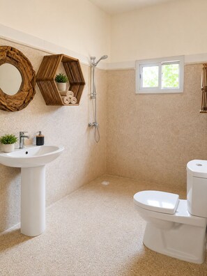 A bathroom with a pedestal sink, toilet, shower, and a window.