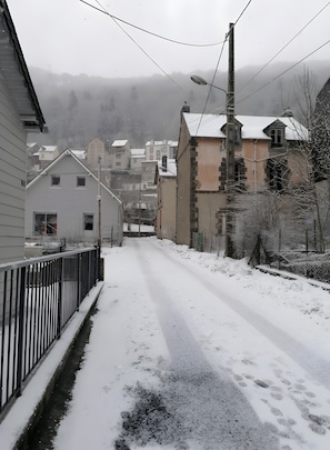 Eine Wohnstraße mit Häusern, einem Metallzaun und einer schneebedeckten Straße.