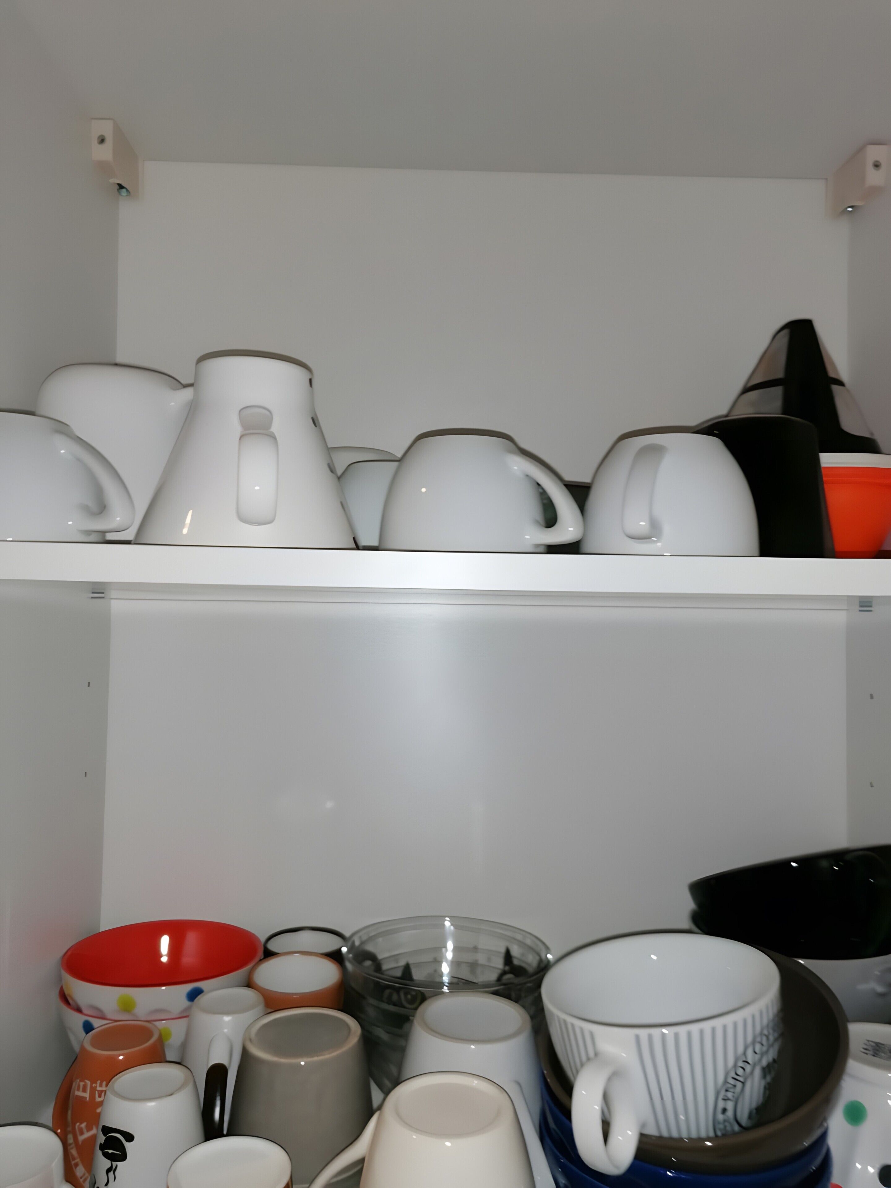 Una cocina con distintos utensilios, incluyendo ollas, sartenes y tazas, ordenados en estantes.