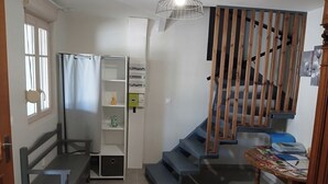 Eine Treppe mit hölzernen Geländern, eine Sitzbank, ein kleiner Tisch mit Gegenständen und ein Regal mit Kartons.
