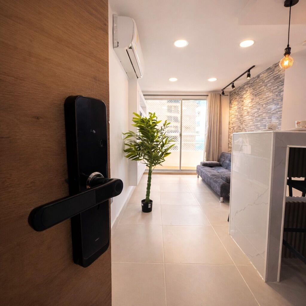 A hallway with a modern door, a potted plant, a sofa, and a stone wall.