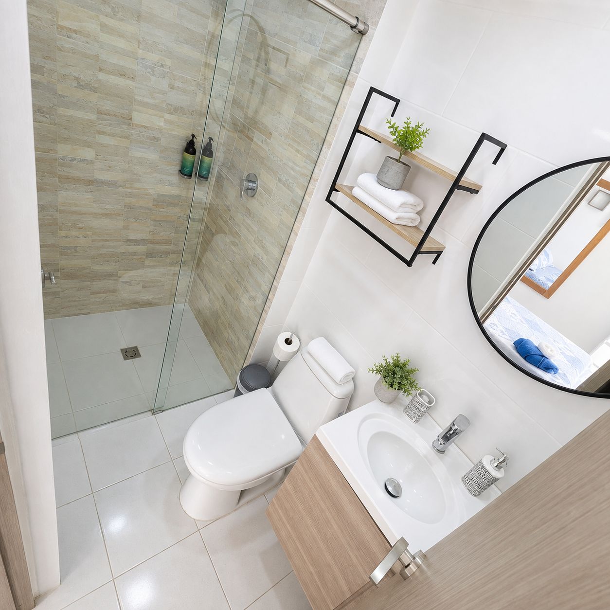 Et moderne badeværelse med brusekabine i glas, toilet, vask med spejl og håndklædestang.