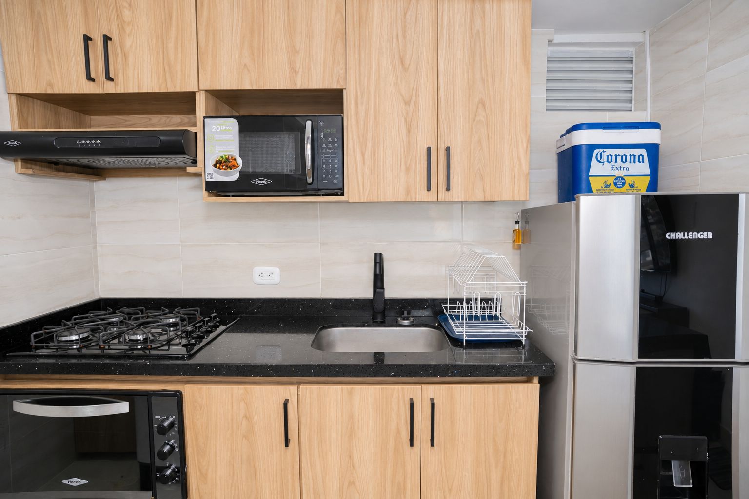 Una cocina moderna con armarios de madera, microondas, estufa a gas, lavavajillas y refrigerador.