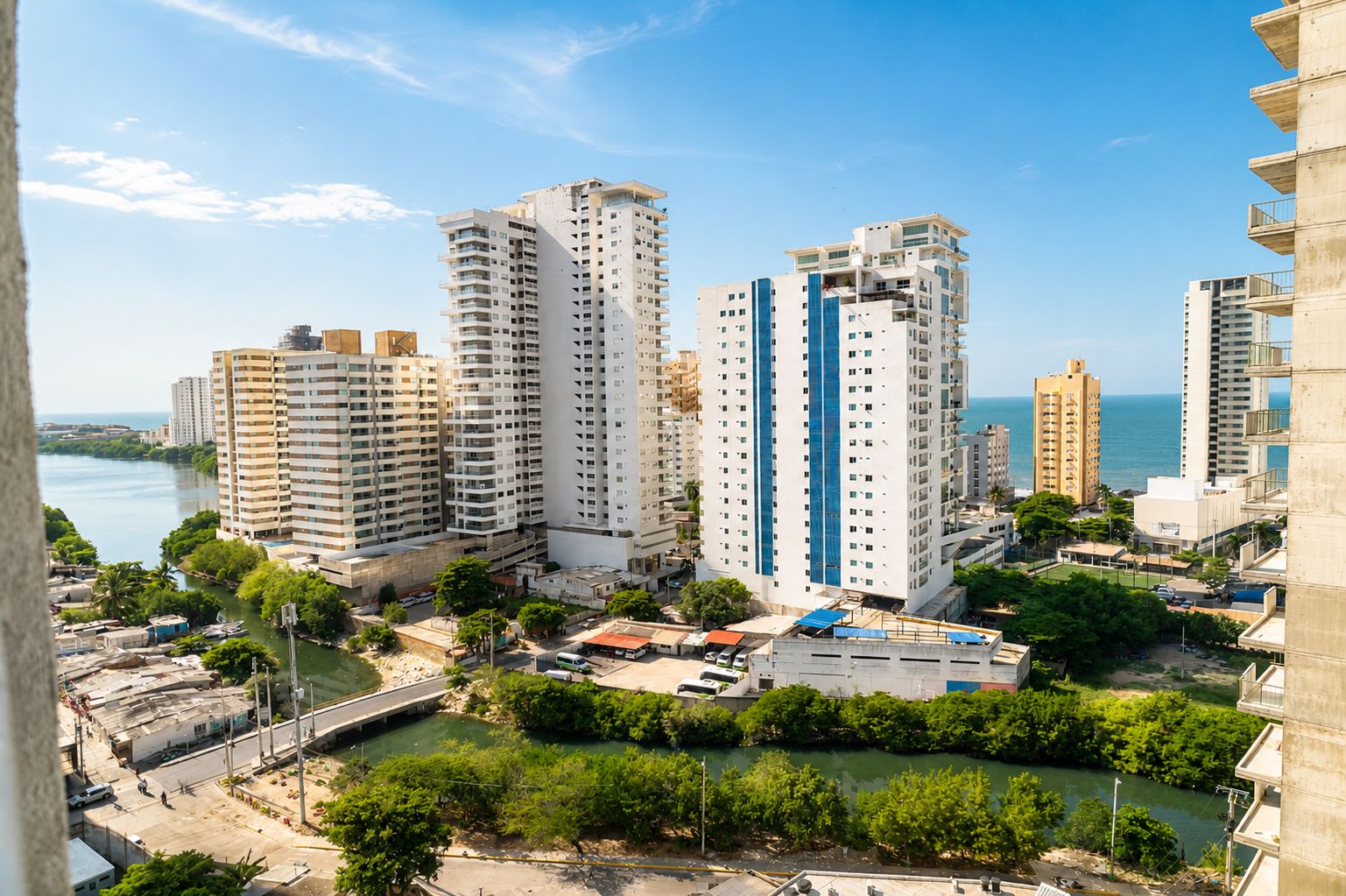 A high-rise residential building complex with multiple balconies, located near a body of water.