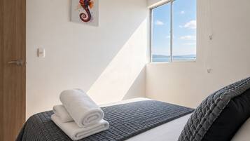 Ein Schlafzimmer mit Bett, Fenster mit Blick, Tür und einem an der Wand befestigten Thermostat.