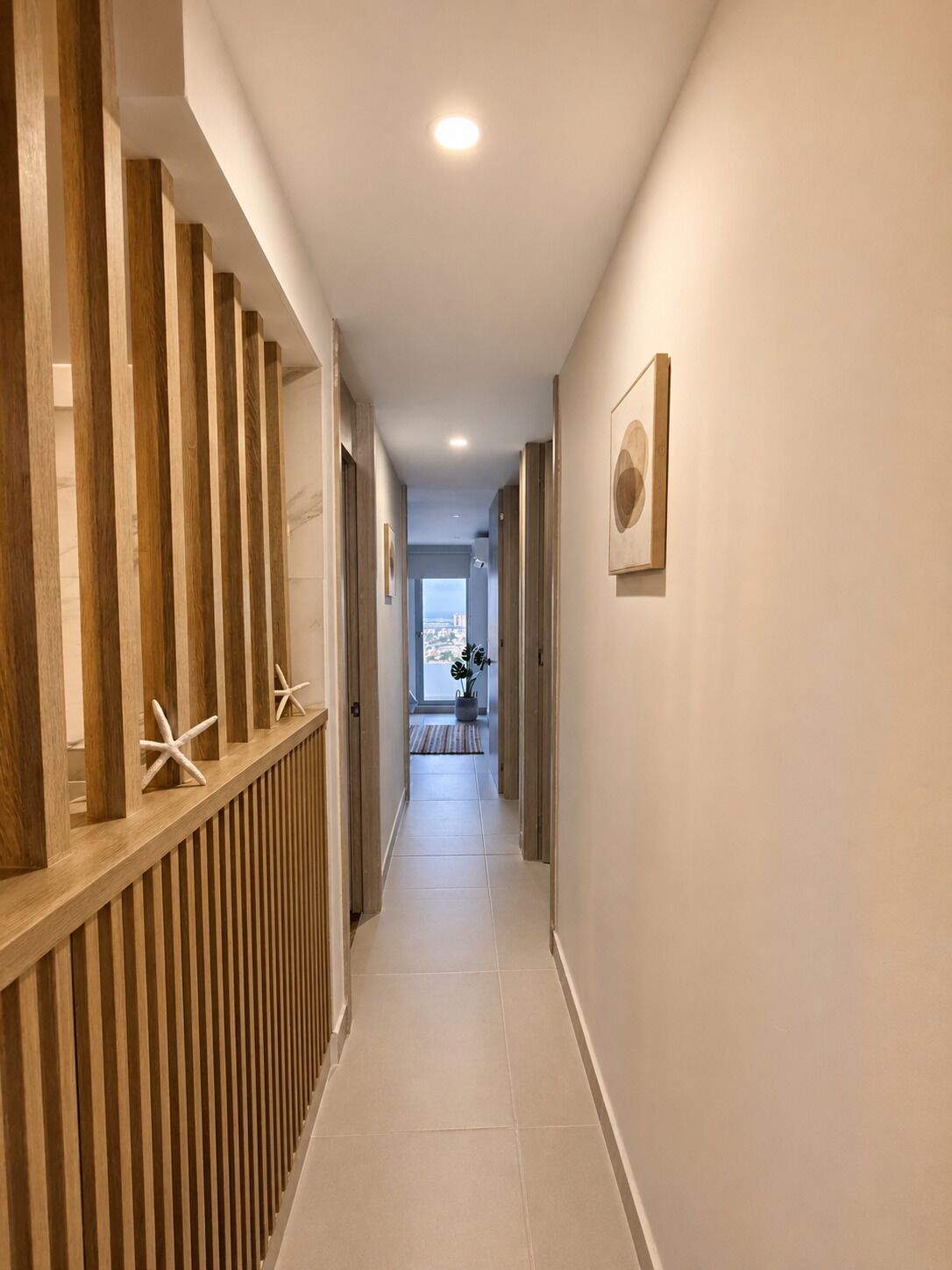 Un pasillo con paneles de madera, suelo de baldosas y un cuadro en la pared.