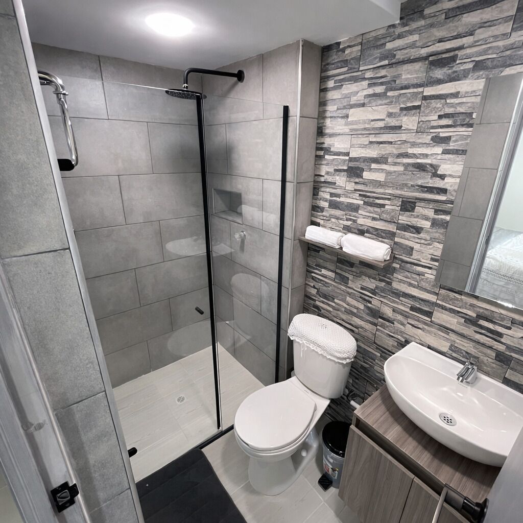Un bagno moderno con doccia vetro, servizi igienici e lavandino.