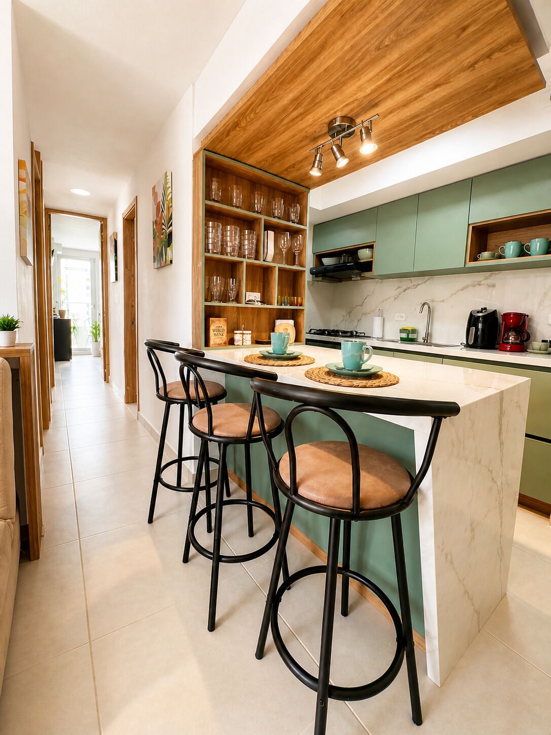 Una cocina moderna con una isla central, taburetes de bar, techo de madera y vista al área de comedor.