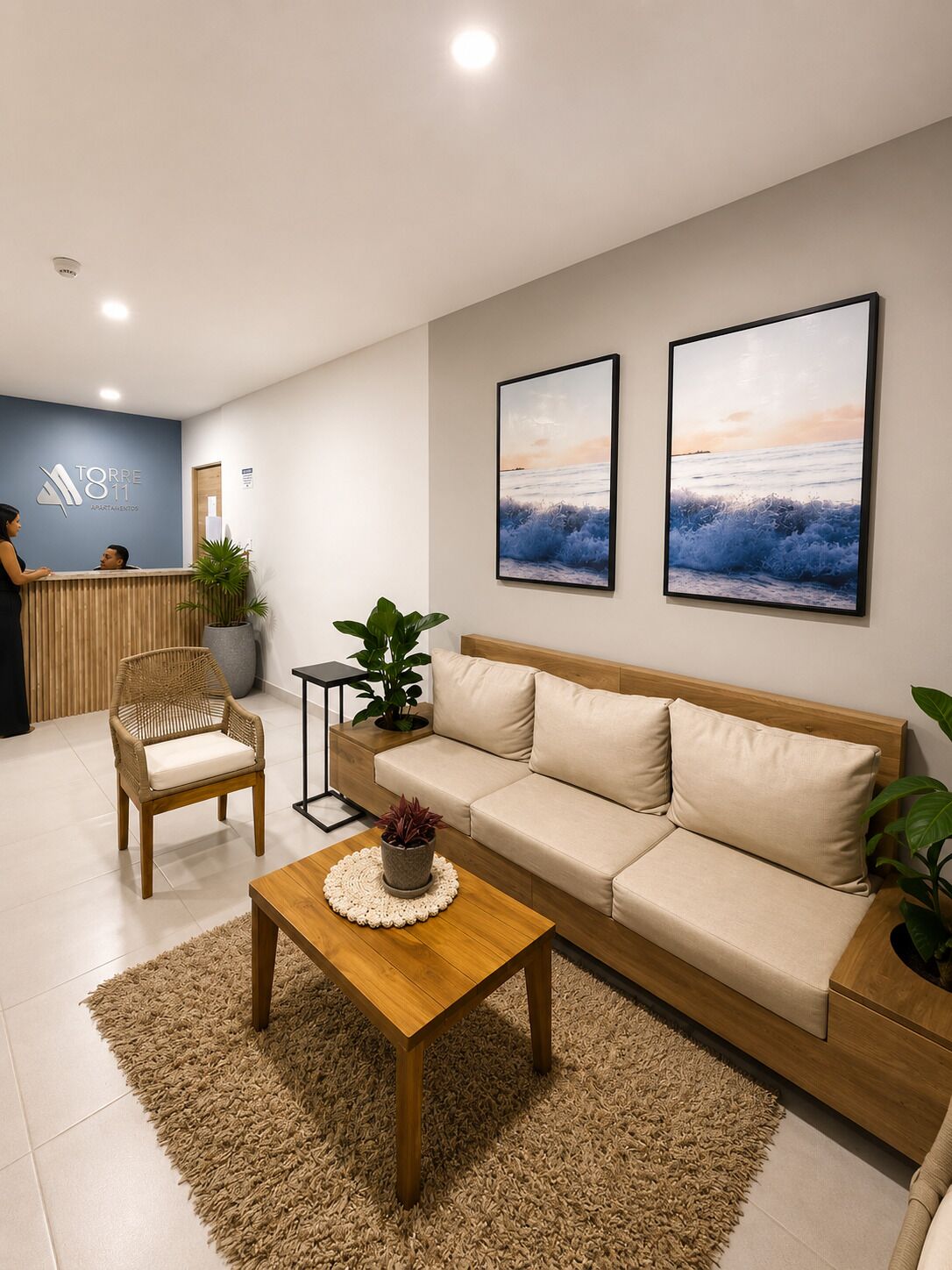 A modern reception area with a reception desk, a sofa, a chair, and two framed pictures on the wall.