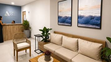 A modern reception area with a reception desk, a sofa, a chair, and two framed pictures on the wall.