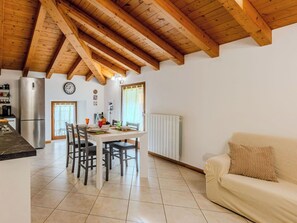 Eine Küche mit Holzbalkendecke, einem Esstisch mit Stühlen, einem Kühlschrank und einer Heizung.