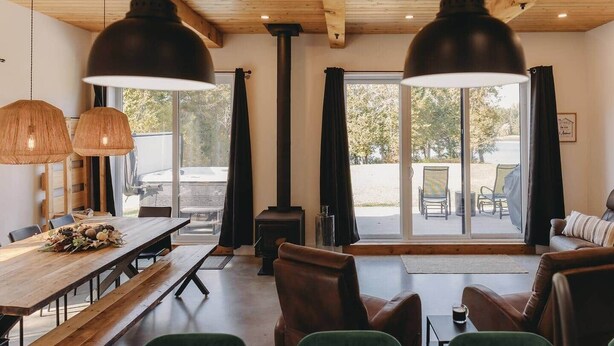Un intérieur chaleureux avec une table à manger en bois, des bancs, un canapé et une cheminée.