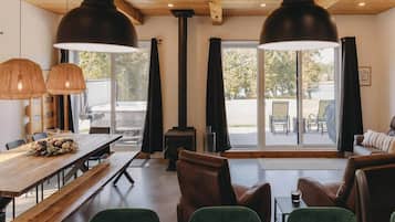 Un intérieur chaleureux avec une table à manger en bois, des bancs, un canapé et une cheminée.