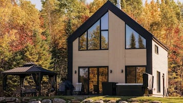Une maison moderne à deux étages, dotée de grandes fenêtres, d’un patio couvert et d’un chemin en pierre.