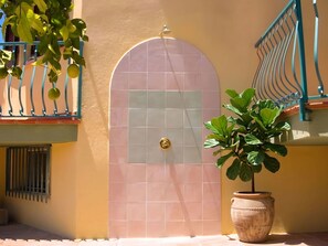 Ein Gebäude mit einer gefliesten Tür, einem Balkon mit Metallgeländer und einem Blumentopf.