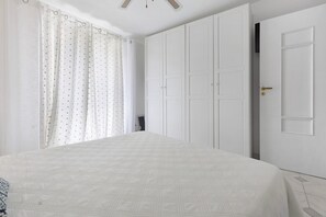Un dormitori amb un llit, un armari i una porta.