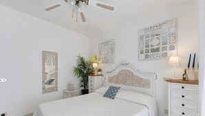 Un dormitorio con cama, cómoda, mesita de noche, espejo y decoración en la pared.
