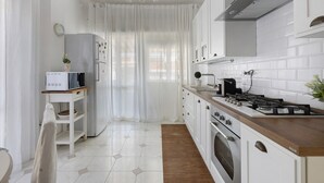 Una cocina moderna con armarios blancos, encimera de madera, estufa a gas y horno empotrado.