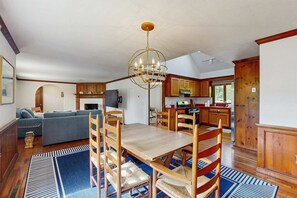 A spacious living area with a dining table, wooden chairs, a chandelier, and a blue patterned rug. - Charming Dog Friendly North Chatham Ranch (Chatham)