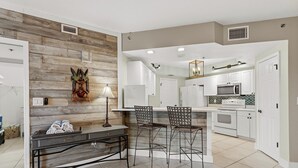 Una cucina moderna con mobili bianchi, un forno a microonde integrato e una parete decorativa in legno.