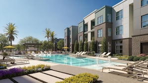 A modern hotel with a swimming pool, lounge chairs, and palm trees.