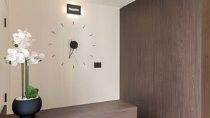 Zona de recepción con un reloj, un cartel de recepción y una planta en maceta.