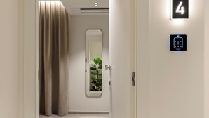 Corredor moderno com porta marcada '4', fechadura eletrônica e espelho refletindo uma planta.