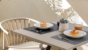 Una mesa con un plato de comida, un vaso de jugo y una pequeña planta.