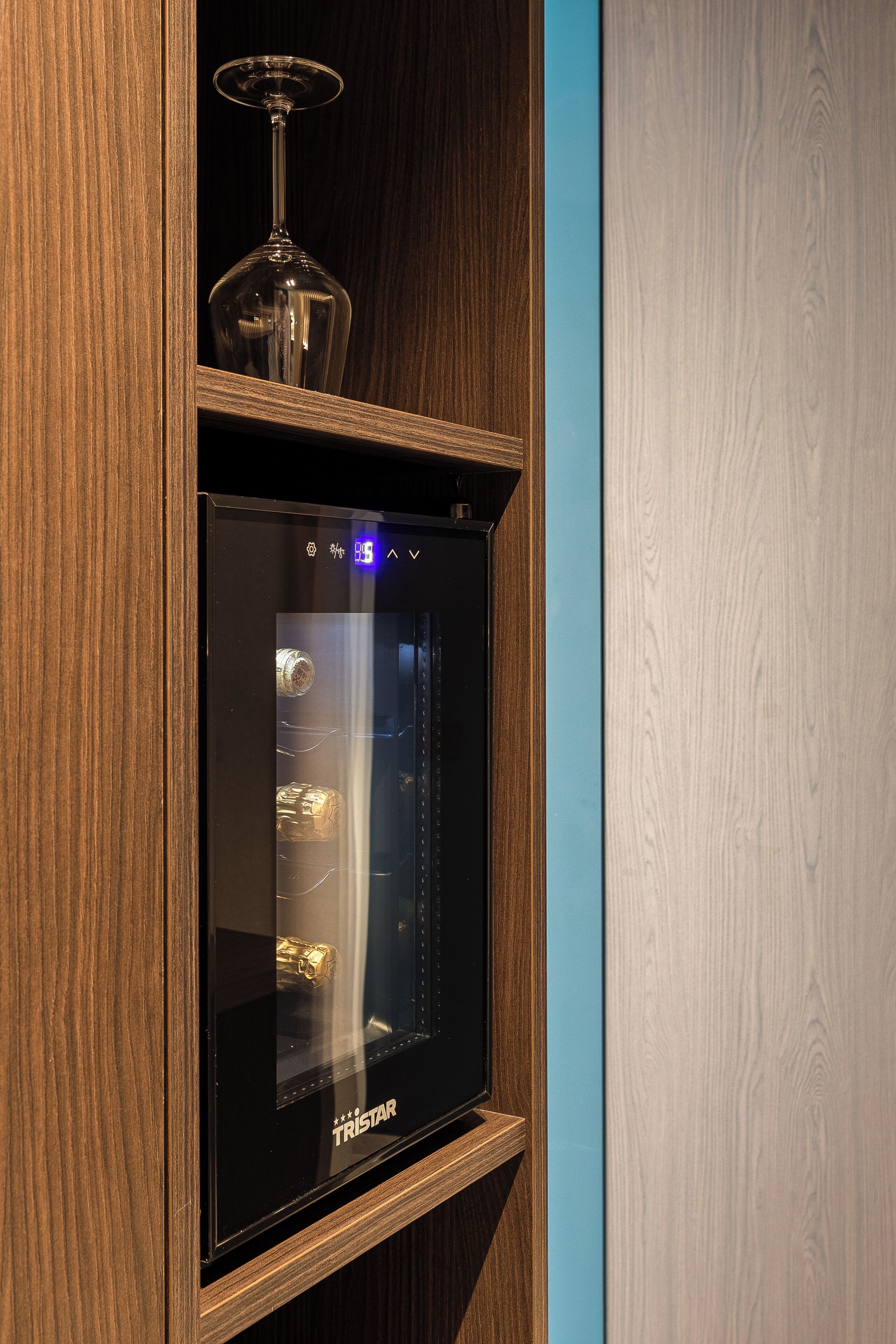 Eine Vitrine mit Glastür, die ein Weinglas und eine Flasche enthält.