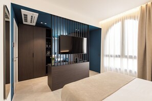 Una habitación de hotel moderna con una cama, un televisor montado en un panel de madera oscura, un armario y una ventana con cortinas.