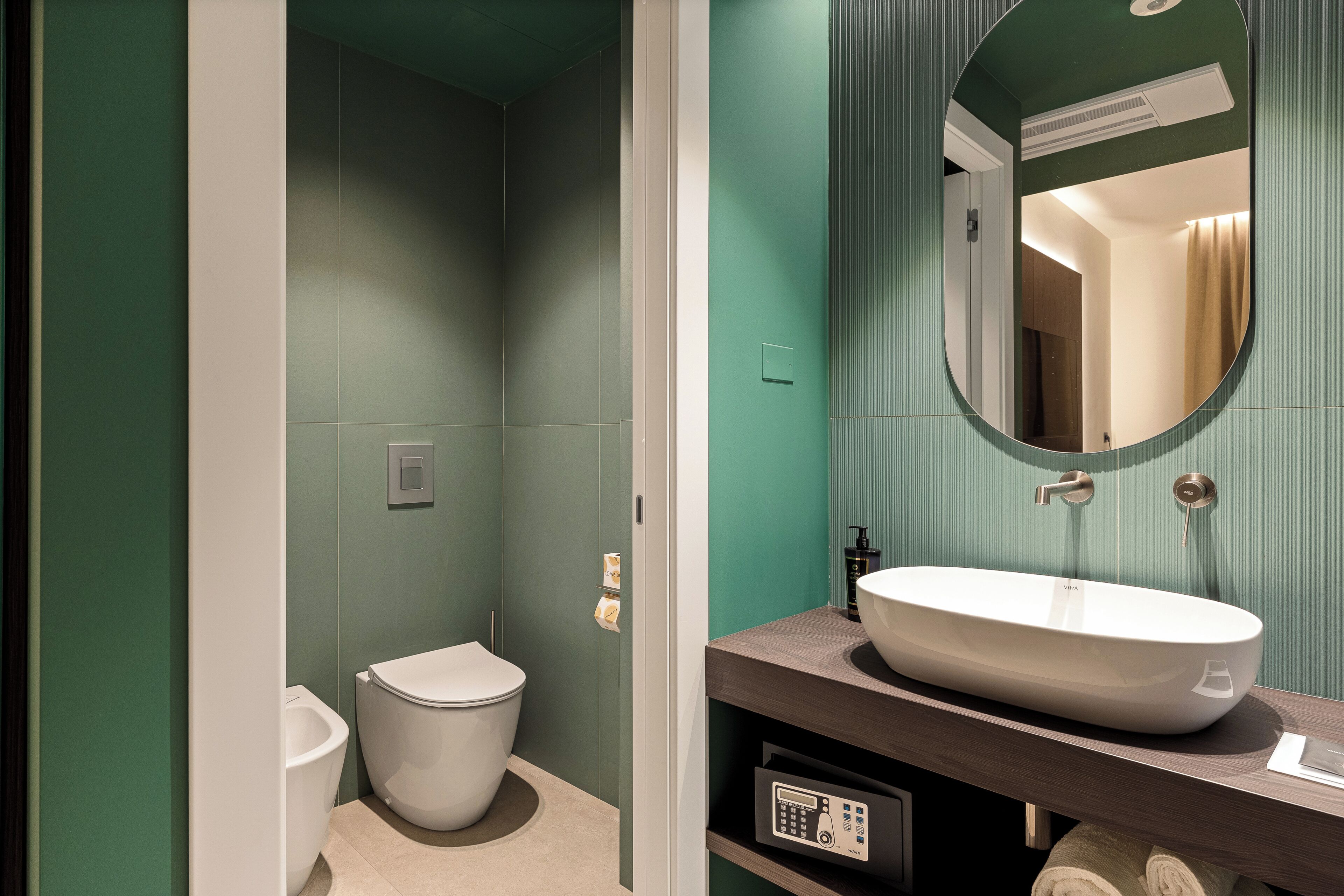 A bathroom with a toilet, a sink, and a mirror.