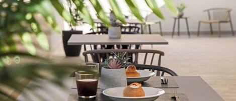 A dining table with a plate of food, a glass of beverage, and a small potted plant.