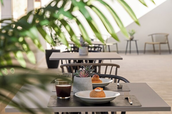 A dining table with a plate of food, a glass of beverage, and a small potted plant.
