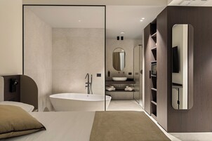 Un baño moderno con una bañera independiente, un espejo grande y un lavabo empotrado.