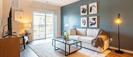 A modern living room with a sofa, coffee table, and artwork on the wall.