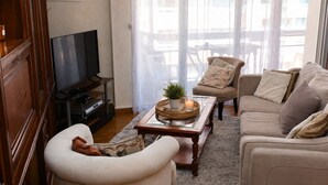 Ein Wohnzimmer mit Fernseher, einer Couch, einem Sessel und einem Couchtisch mit Dekoration.