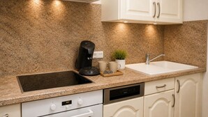 Eine Küche mit Granit Arbeitsplatte, einer Kaffeemaschine, einem Spülbecken und einem Herd.