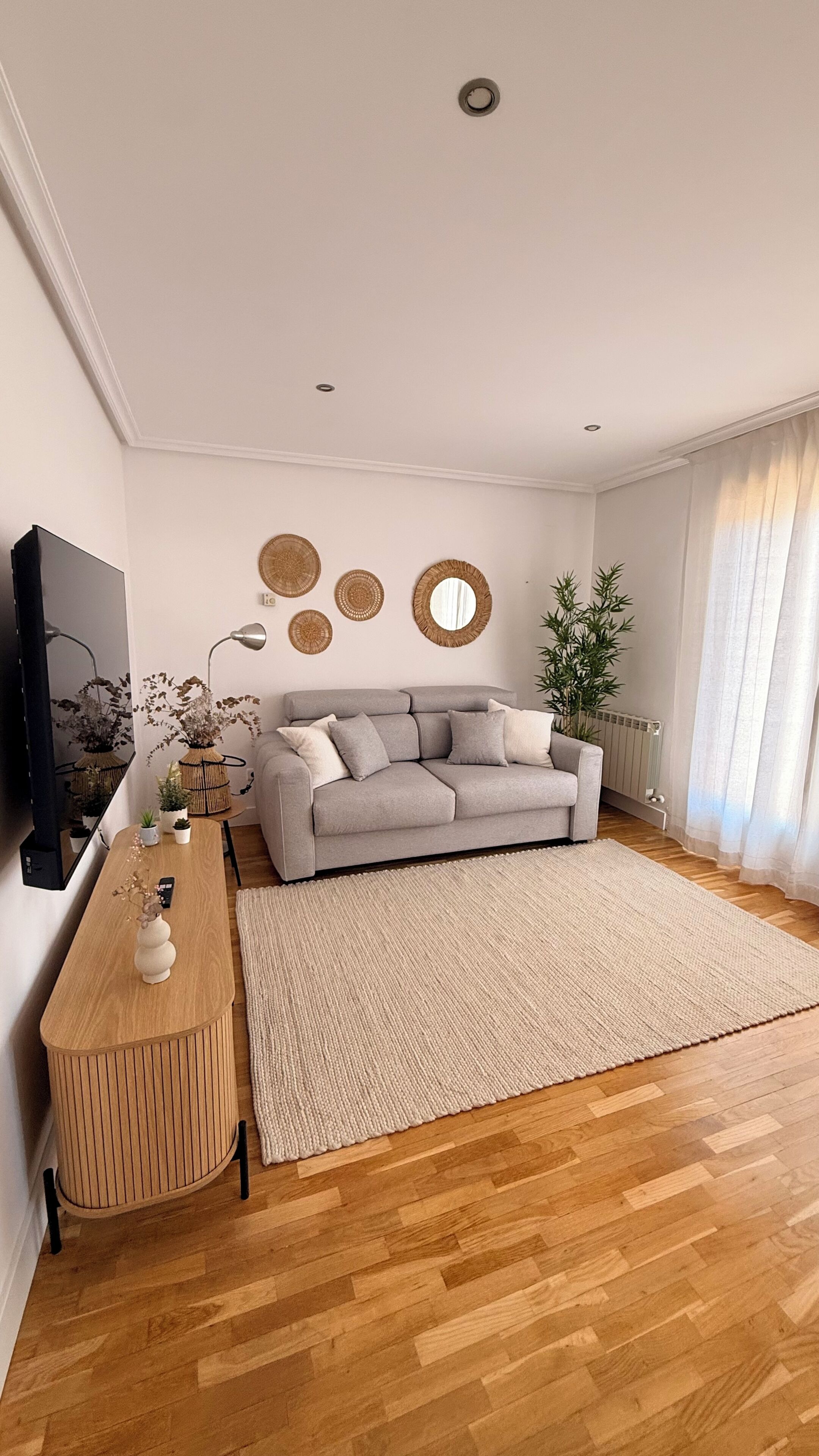 A modern living room with a grey sofa, wooden coffee table, and decorative wall art.