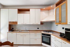 Eine moderne Küche mit weißen Schränken, einem Gasherd, einem Backofen und einer Holzarbeitsplatte.