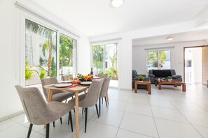 Una sala de estar moderna con comedor, ventanas amplias y vista a zonas verdes.