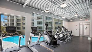 Un gimnasio con cintas de correr, elípticas y una piscina.