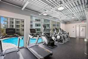 Ein Fitnessstudio mit Laufbändern, Crosstrainern und einem Schwimmbad.