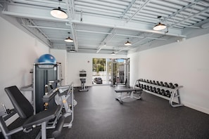 Ein Fitnessraum mit Trainingsgeräten, Kurzhanteln und einer Bank.