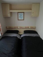 A room with two beds, a framed picture on the wall, and a decorative headboard.