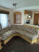 A compact living space with a sofa, a kitchenette, and a window with curtains.